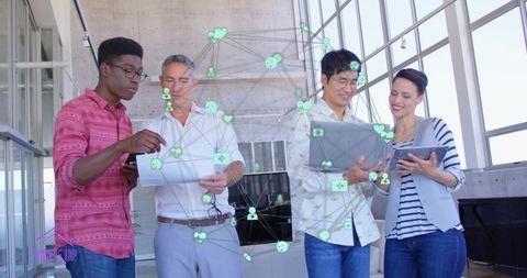 Collaborating team sharing tablets and laptop with augmented network overlay in bright atrium