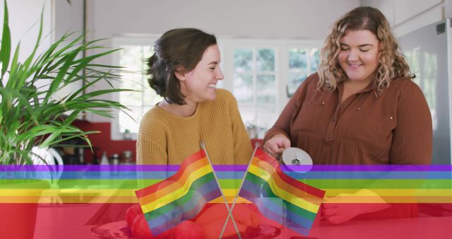 Image of rainbow flag over lesbian couple preparing coffee in kitchen. lgbt rights and equality concept digitally generated image.