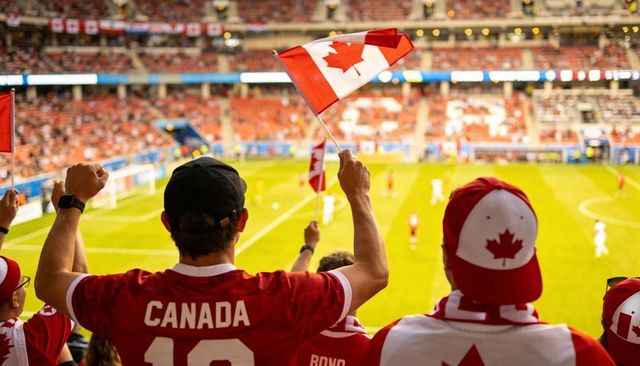 Canadian soccer supporters waving flags and cheering in packed stadium