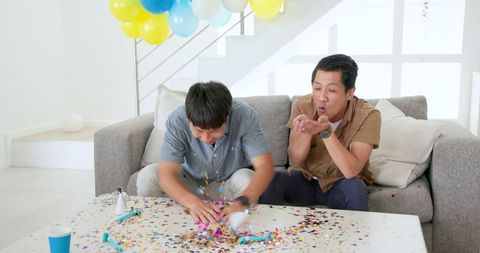Father and Son Celebrating with Confetti in Living Room
