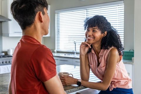 Diverse couple chatting at kitchen island over coffee, casual morning connection, warm smiles