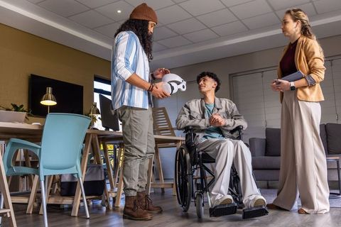 Rehabilitation team demonstrating vr headset to wheelchair user during collaborative therapy