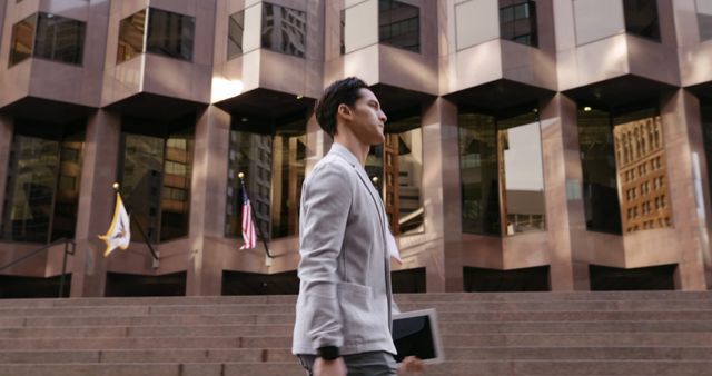 Image of a businessman walking confidently in front of a modern office building in an urban setting. Ideal for use in business websites, career-oriented publications, corporate brochures, and articles focused on professional or urban lifestyles.