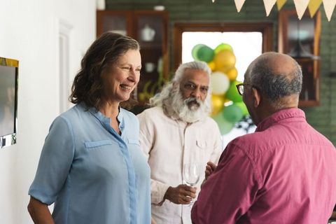 Mature friends chatting at home during casual celebration with balloons and bunting