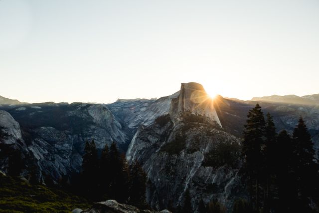 Beautiful sunset casting a glow over Half Dome peak in Yosemite National Park. Perfect for travel brochures, adventure-themed advertising, nature conservation campaigns, and outdoor travel blogs.