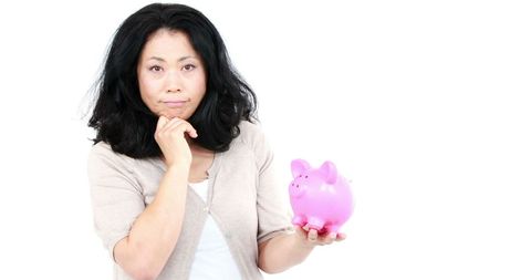 Thoughtful woman contemplating finances with piggy bank