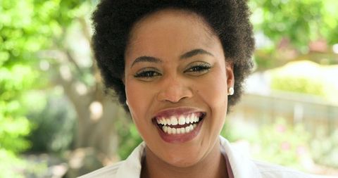 African American Woman Smiling Outdoors in Sunlit Garden