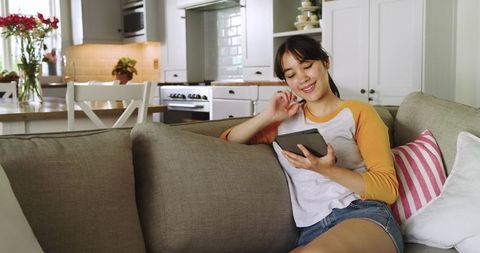 Young Woman Relaxing on Couch with Tablet in Modern Living Room