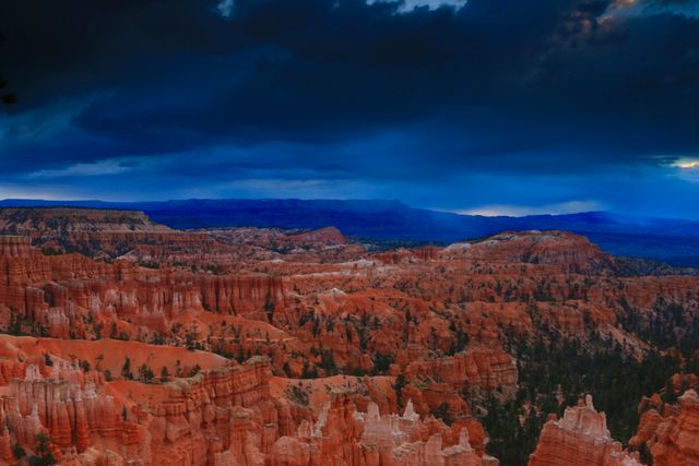Depicts Bryce Canyon National Park with its iconic red rock formations under a dramatic, stormy sky at sunset. Ideal for promoting travel destinations, geology education materials, outdoor adventure activities, and nature conservation efforts.