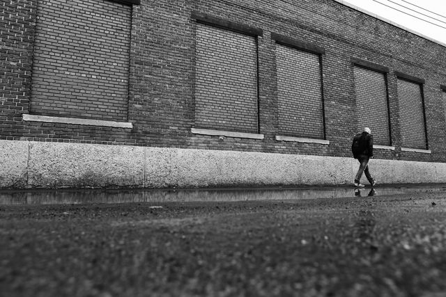 Lonely Person Walking Beside Brick Building on Rainy Day in Black and White - Download Free Stock Photos Pikwizard.com