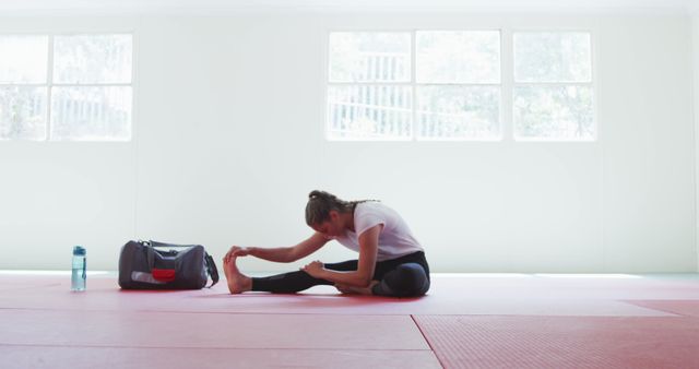 Woman Stretching on Gym Floor in Bright Room - Download Free Stock Images Pikwizard.com