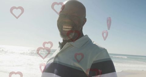 Joyful senior man enjoying beach with heart symbol overlay