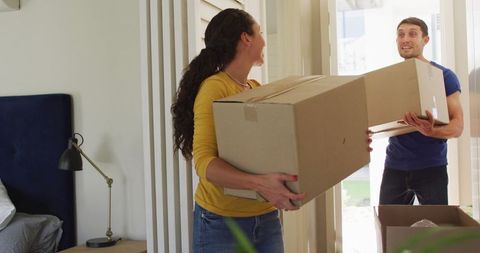 Happy couple moving into new home together with cardboard boxes