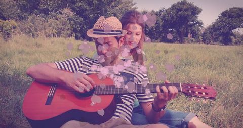 Romantic Couple Playing Guitar in Nature with Heart Overlay