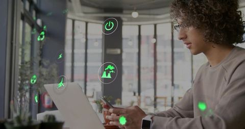 Remote worker using smartphone and laptop with green sustainability holograms in cafe