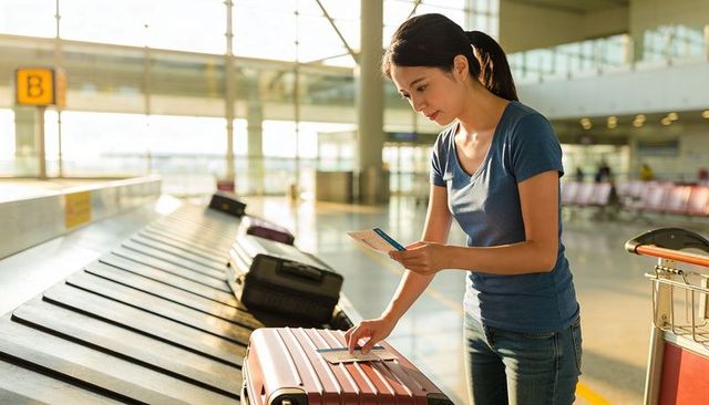 Placing passport and boarding pass on rose-gold suitcase at airport baggage claim