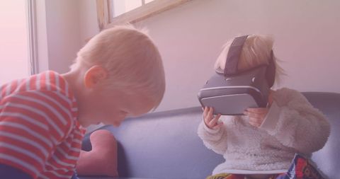 Young siblings enthralled with vr technology in living room