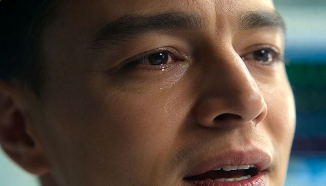 Tearful young man shedding single tear, revealing vulnerable emotional gaze close-up