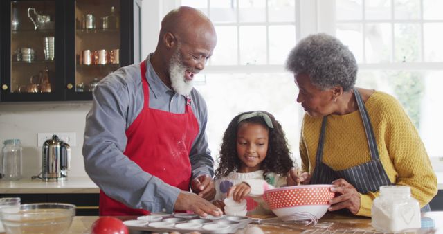 This image is great for advertisements, blogs, and articles focused on family activities, bonding, and intergenerational relationships. It captures a warm and joyful moment of grandparents and their granddaughter baking together, emphasizing themes of love, togetherness, and the joy of cooking as a family. Perfect for use in posters, greeting cards, lifestyle websites, and magazines promoting family values and home activities.