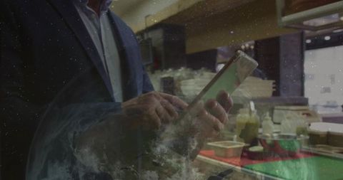Businessman tapping tablet at cafe counter with condiments and copy space for business use