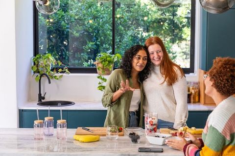 Diverse friends preparing infused water in modern kitchen