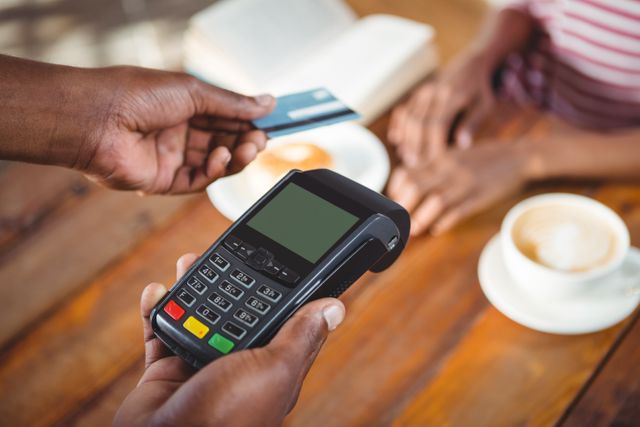 Waiter holding credit card machine in cafe