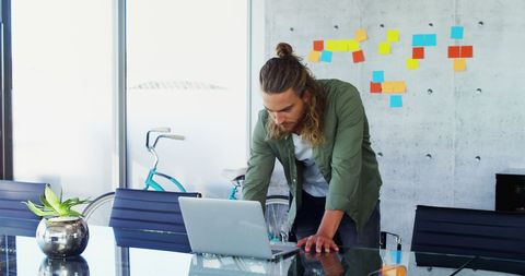 Entrepreneur Checking Work on Laptop in Creative Office Environment