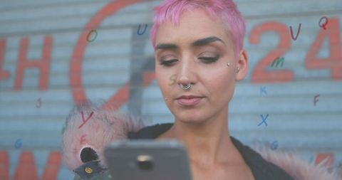 Trendy Young Woman with Pink Hair Using Smartphone Against Urban Wall