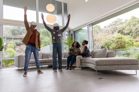 Multiracial friends experiencing virtual reality at modern home while others using tablet