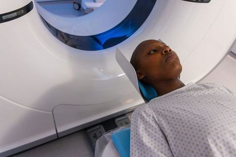 Calm african woman undergoing ct scan in modern radiology suite wearing hospital gown