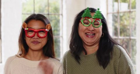 Mother and daughter smiling with festive holiday glasses