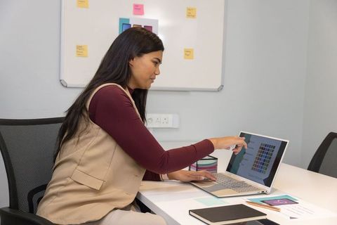 Asian woman pointing at laptop color palette during modern design meeting