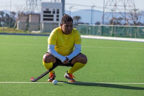 Field Hockey Player Crouching on Turf Awaiting Action