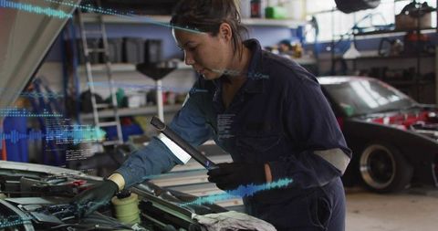 Female mechanic inspecting engine with led lamp and augmented diagnostics in auto garage