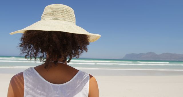 Woman with Curly Hair and Sun Hat Relaxing on Sunny Beach - Download Free Stock Images Pikwizard.com