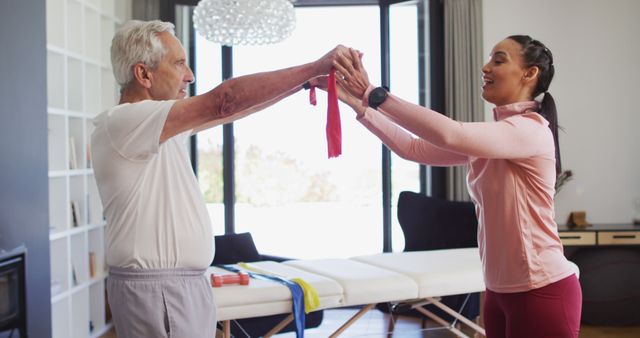 Image of happy biracial female physiotherapist exercising with caucasian senior man. seniors health and nursing home lifestyle concept digitally generated image.