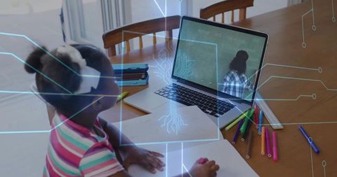 Child studying during online lesson at home with laptop, colorful markers and notebooks