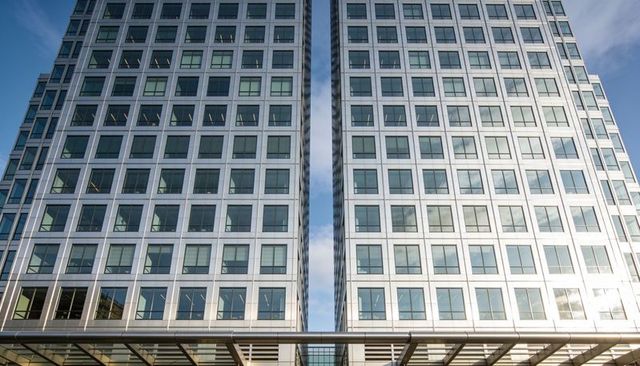 Twin glass office towers rising from plaza with metal canopy and reflective facade