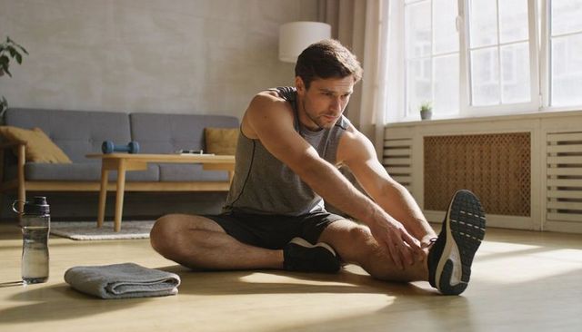 Man stretching after home workout in sunlit minimalist living room