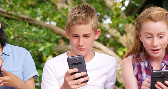 Teenagers Engaging with Smartphones Outdoors - Download Free Stock Images Pikwizard.com