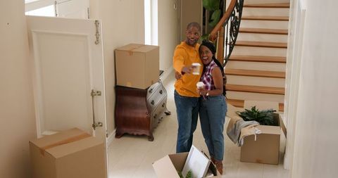 Cheerful Couple Arriving in New Home with Moving Boxes