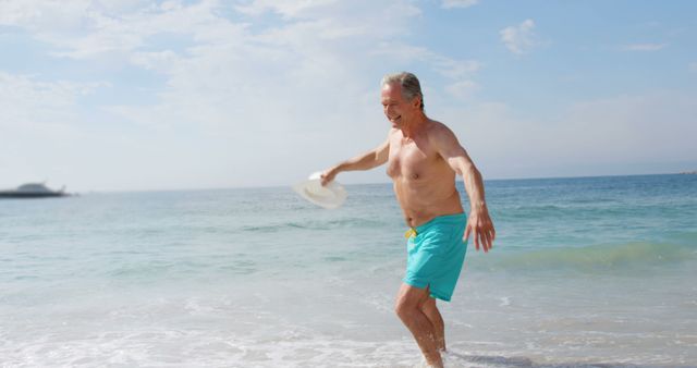 Senior man in blue shorts and hat enjoying his time at the beach. Perfect for use in vacation promotions, travel brochures, health and wellness campaigns, and advertisements targeting the elderly. Depicts leisure, joy, and the carefree essence of a beach holiday.