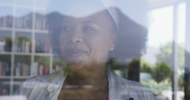 Thoughtful Woman Looking Through Glass Window with Bookshelf in Background - Download Free Stock Images Pikwizard.com