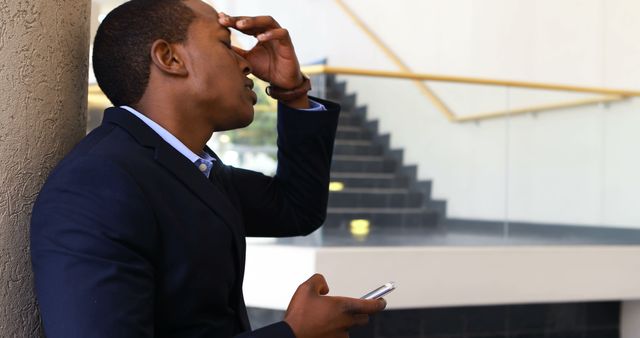 Worried Businessman Holding Phone Leaning Against Wall - Download Free Stock Images Pikwizard.com