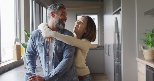 Happy diverse couple wearing casual clothes embracing together in kitchen. Spending quality time at home.