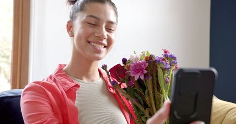 Smiling Young Woman Having Virtual Call Holding Bouquet of Flowers