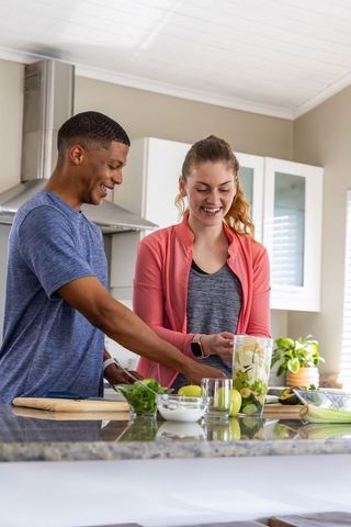 Couple preparing green smoothie on granite island in modern kitchen healthy lifestyle