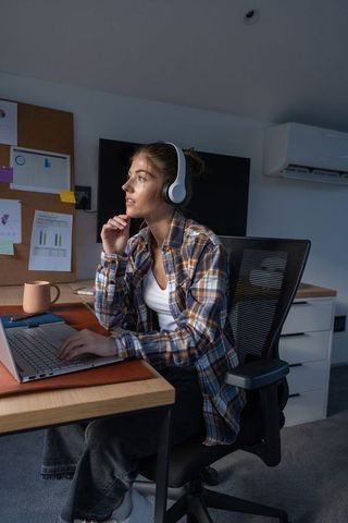 Professional Woman Using Laptop and Headphones in Home Office