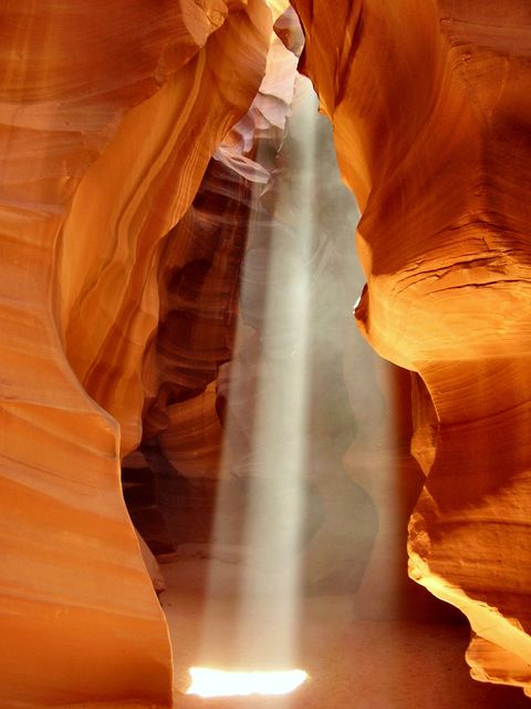 Beautiful sunlight ray streaming through the narrow walls of Antelope Canyon, highlighting the intricate patterns of sandstone formations. This image captures the serene and majestic beauty of one of Arizona's most famous natural spectacles. Perfect for travel websites, nature calendars, geology studies, environmental presentations, and inspirational posters.