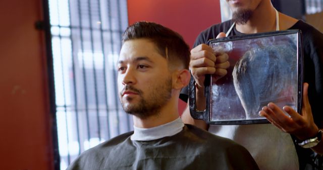 A young Asian man is getting a haircut from a barber, with copy space. Capturing a moment of personal grooming, the image reflects the attention to detail in men's hairstyling.